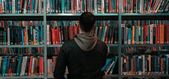 Mann steht vor einem Bücherregal